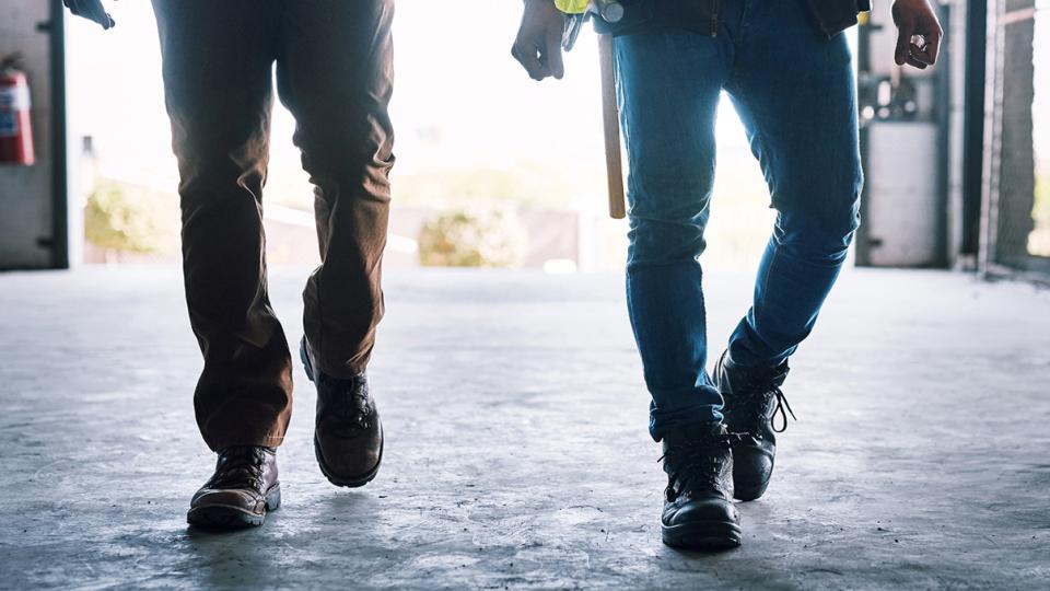 Two people walking inside a sunlit industrial space
